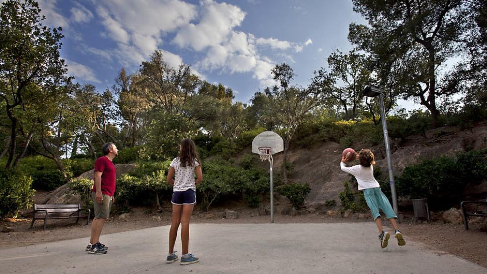Familia jugando en una de las canastas del parque de monterols